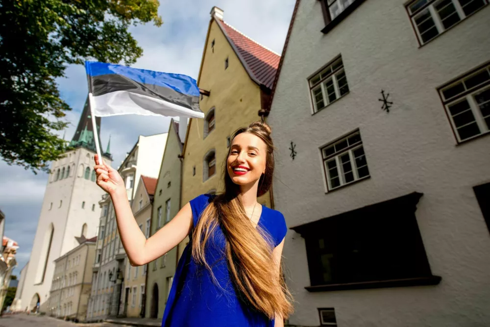 Young female tourist with estonian flag in front of saint Olaf church in the old town of Tallinn. Woman having great vacations in Estonia / Foto: Rosshelen