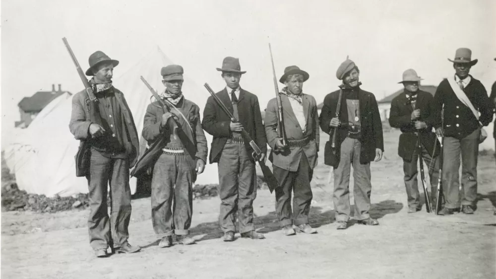 Oboroženi stavkajoči v &scaron;otorskem naselju Ludlow leta 1914. Na fotografiji je mogoče videti bele &scaron;otore, ki jih je zagotovil sindikat United Mine Workers of America, ter pu&scaron;ke z vzvodnim mehanizmom, ki so bile raz&scaron;irjene na obeh straneh spopada. / Foto: Wikipedija