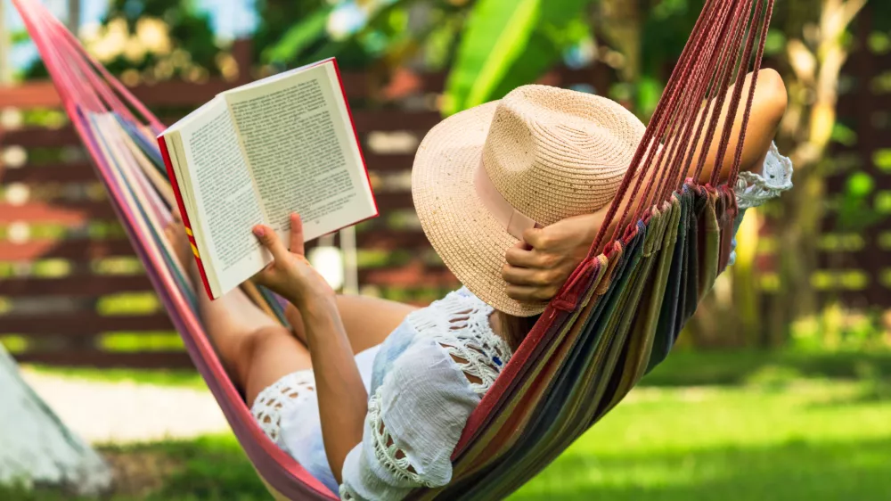Med uživanjem v viseči mreži in branjem knjige. Kaj bi bilo lep&scaron;ega? / Foto: Istock