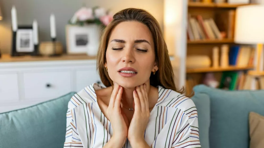 Close up of young woman rubbing her inflamed tonsils, tonsilitis problem, cropped. Woman with thyroid gland problem, touching her neck, girl has a sore throat / Foto: Stefanamer