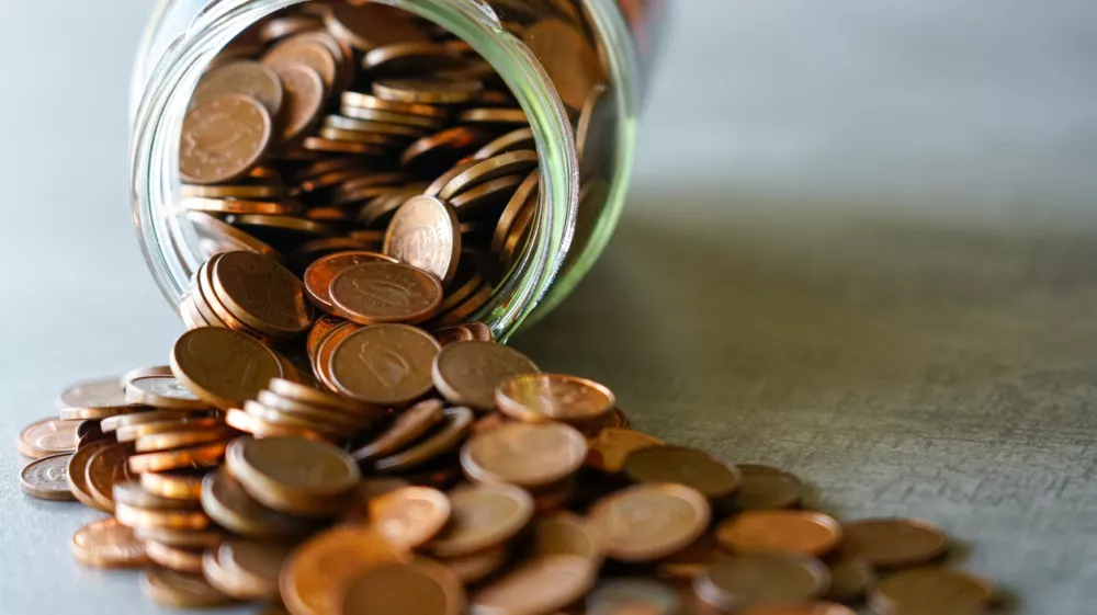 Spilled Glass Jar Full of Copper Euro Cents on a Table Symbolizing Savings, Budgeting, and the Value of Small Change / Foto: Zigmunds Dizgalvis Getty Images