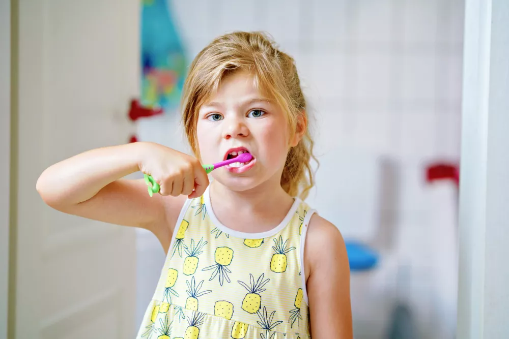 Cute little girl with a toothbrush and toothpaste in her hands cleans her teeth and smiles. Happy preschool child brushing first teeth / Foto: Romrodinka Getty Images