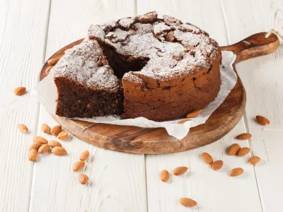 Italian Torta Caprese is a decadent, flourless cake made with dark chocolate and almonds closeup on the wooden board on the table. Horizontal / Foto: Alleko