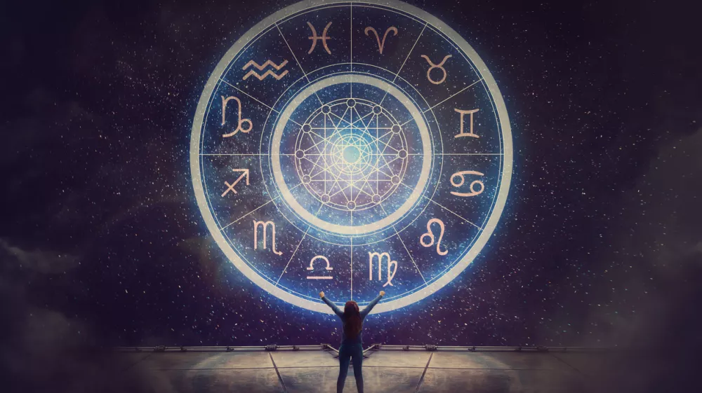 Woman raising hands looking at the night sky. Astrological wheel projection, choose a zodiac sign. Trust horoscope future predictions, consulting stars. Power of universe, astrology esoteric concept. / Foto: Bulat Silvia Getty Images