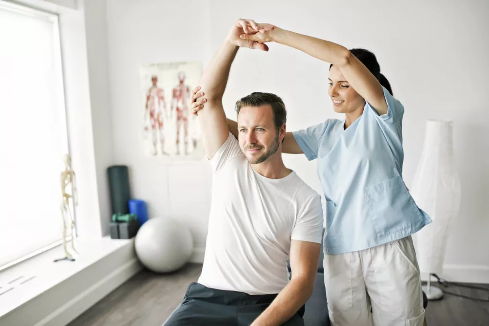 A physiotherapist doing treatment with patient in bright office / Foto: Lsophoto Getty Images