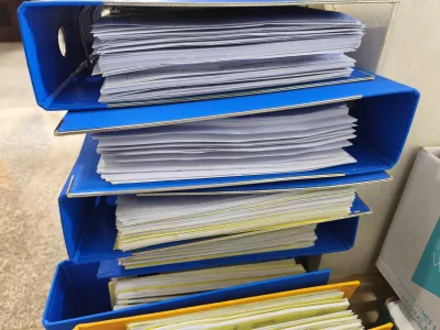 close-up view of colorful office binders stuffed with paperwork, illustrating heavy administrative workload, organization challenges, and office documentation processes / Foto: Mathlaul Anwar Getty Images