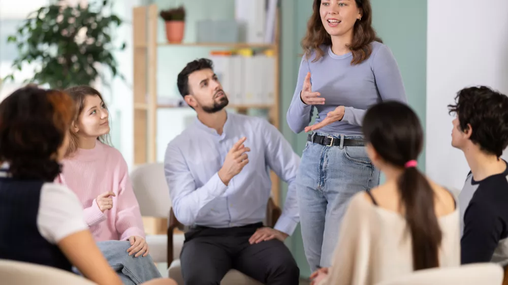 Students are arranged in circle, and girl participant stands up. Company managers during training, introductory training for staff, professional development courses, educational seminar. / Foto: Jackf Getty Images