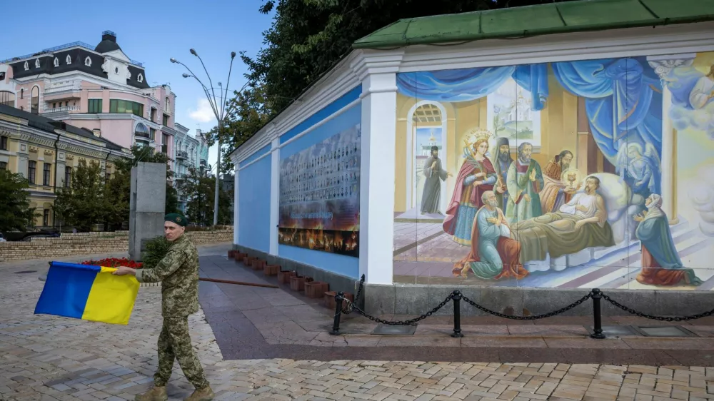 A soldier carries a Ukrainian national flag outside St. Michael's Golden-Domed Monastery, amid Russia's attack on Ukraine, in Kyiv, Ukraine August 25, 2025. REUTERS/Thomas Peter