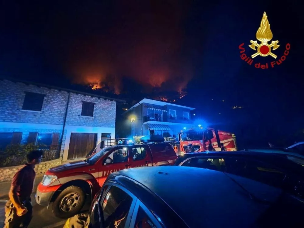 A fire engine and an emergency vehicle stand near residential buildings as a wildfire burns on a hillside in Tignale, in the province of Brescia, Italy, in this handout image released on August 8, 2026. Vigili del Fuoco/Handout via REUTERS ATTENTION EDITORS &ndash; THIS IMAGE WAS PROVIDED BY A THIRD PARTY. LOGO FROM SOURCE. BEST QUALITY AVAILABLE.