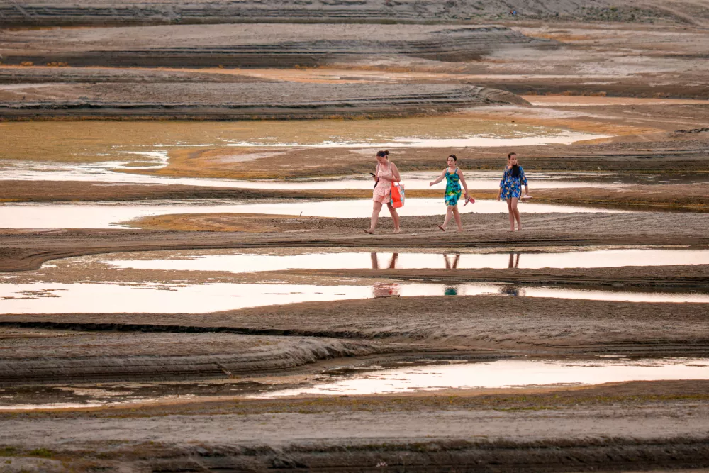 People walk on a sandbank on the Danube River as usually submerged areas are exposed amid exceptionally low water levels, in Rasova, Romania, Friday, Aug. 7, 2026. (AP Photo/Andreea Alexandru)