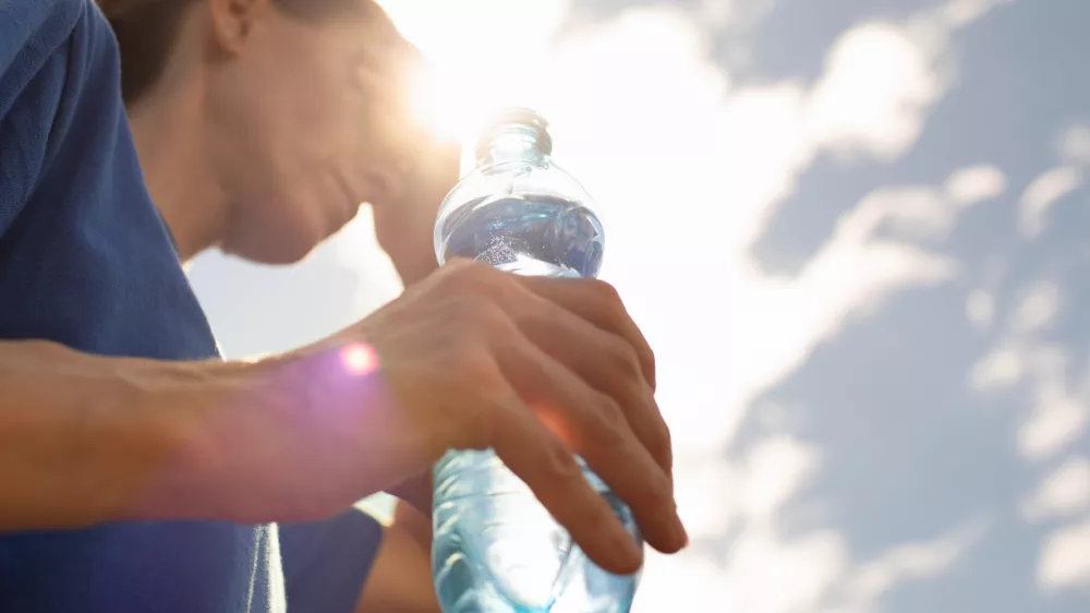 Woman drinking water in extreme summer heat wave.