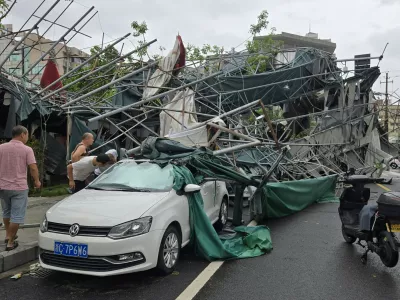 People look inside a car pinned by a fallen scaffolding structure after Typhoon Dolphin affected the area, in Wenzhou in eastern China's Zhejiang province, Monday, Aug. 10, 2026. (Chinatopix Via AP)