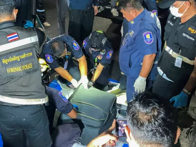 Forensic technicians examine a suitcase, in which police later found the body of a 17-year-old Thai girl, after it was recovered from a grassy area near a railway track in Pattaya City, Thailand, June 27, 2026. Picture taken with a mobile phone. REUTERS/Teerasak Suttativong