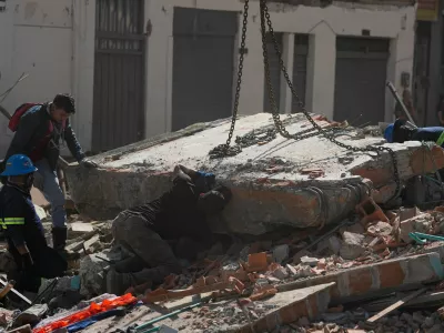 Workers secure a section of the collapsed structure with chains before it is lifted by a crane the day after an earthquake struck Pereira, Colombia, Tuesday, Aug. 11, 2026. (AP Photo/Fernando Vergara)