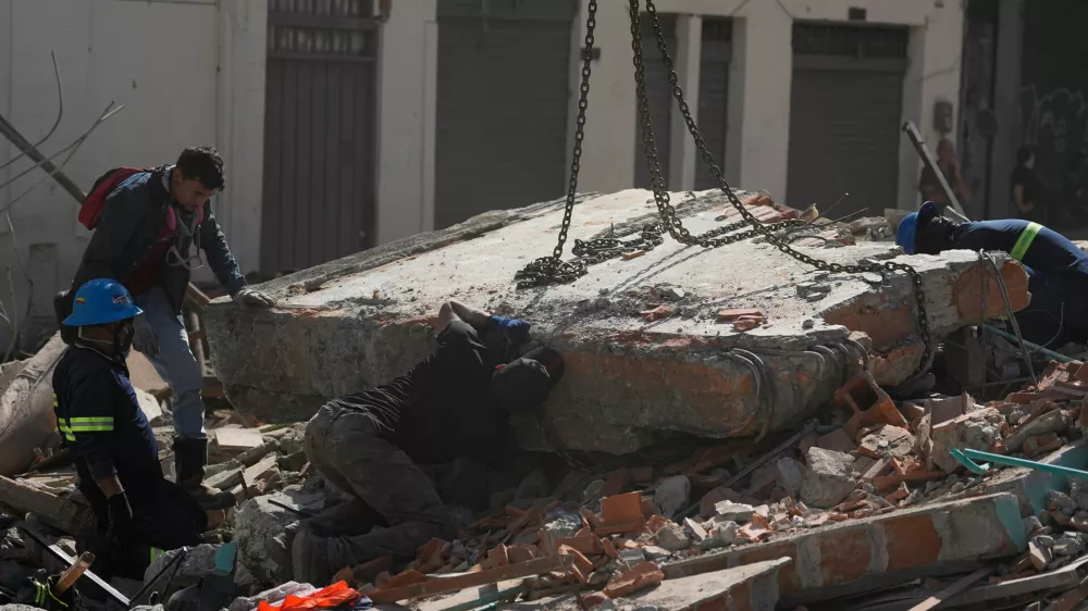 Workers secure a section of the collapsed structure with chains before it is lifted by a crane the day after an earthquake struck Pereira, Colombia, Tuesday, Aug. 11, 2026. (AP Photo/Fernando Vergara)