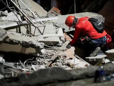 A rescuer searches for survivors under the rubble at the Torres de Limonar building in the aftermath of an earthquake, in Cali, Colombia, August 11, 2026. REUTERS/Sergio Acero