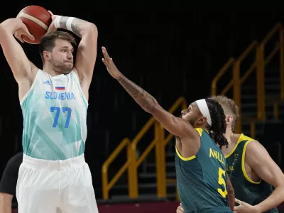 Slovenia's Luka Doncic (77) looks to pass over Australia's Patty Mills (5) during the men's bronze medal basketball game at the 2020 Summer Olympics, Saturday, Aug. 7, 2021, in Tokyo, Japan. (AP Photo/Eric Gay)