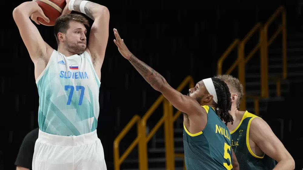Slovenia's Luka Doncic (77) looks to pass over Australia's Patty Mills (5) during the men's bronze medal basketball game at the 2020 Summer Olympics, Saturday, Aug. 7, 2021, in Tokyo, Japan. (AP Photo/Eric Gay)