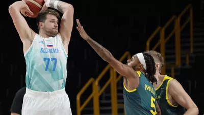 Slovenia's Luka Doncic (77) looks to pass over Australia's Patty Mills (5) during the men's bronze medal basketball game at the 2020 Summer Olympics, Saturday, Aug. 7, 2021, in Tokyo, Japan. (AP Photo/Eric Gay)