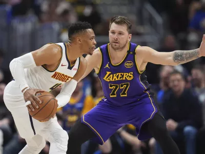 Denver Nuggets guard Russell Westbrook, left, looks to pass the ball as Los Angeles Lakers guard Luka Doncic defends in the first half of an NBA basketball game Saturday, Feb. 22, 2025, in Denver. (AP Photo/David Zalubowski)