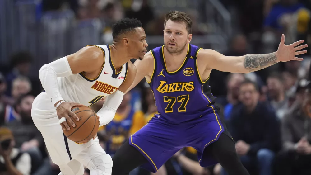 Denver Nuggets guard Russell Westbrook, left, looks to pass the ball as Los Angeles Lakers guard Luka Doncic defends in the first half of an NBA basketball game Saturday, Feb. 22, 2025, in Denver. (AP Photo/David Zalubowski)