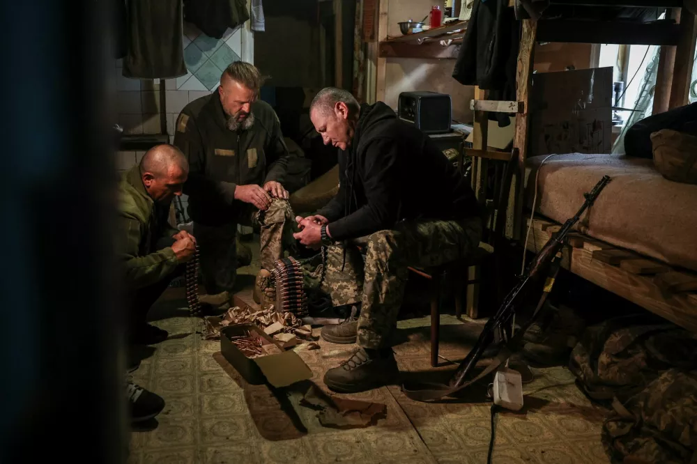 Serhii Krynitskyi, 42, a serviceman of the 24th Separate Mechanized Brigade of the Ukrainian Armed Forces, who spent 346 days at an isolated frontline position in the town of Chasiv Yar, Donetsk region, helps his fellow soldiers load machine gun cartridges on his first day back on duty after recovery, amid Russia's attack on Ukraine, in the frontline city of Kramatorsk in Donetsk region, Ukraine, May 27, 2026. REUTERS/Alina Smutko