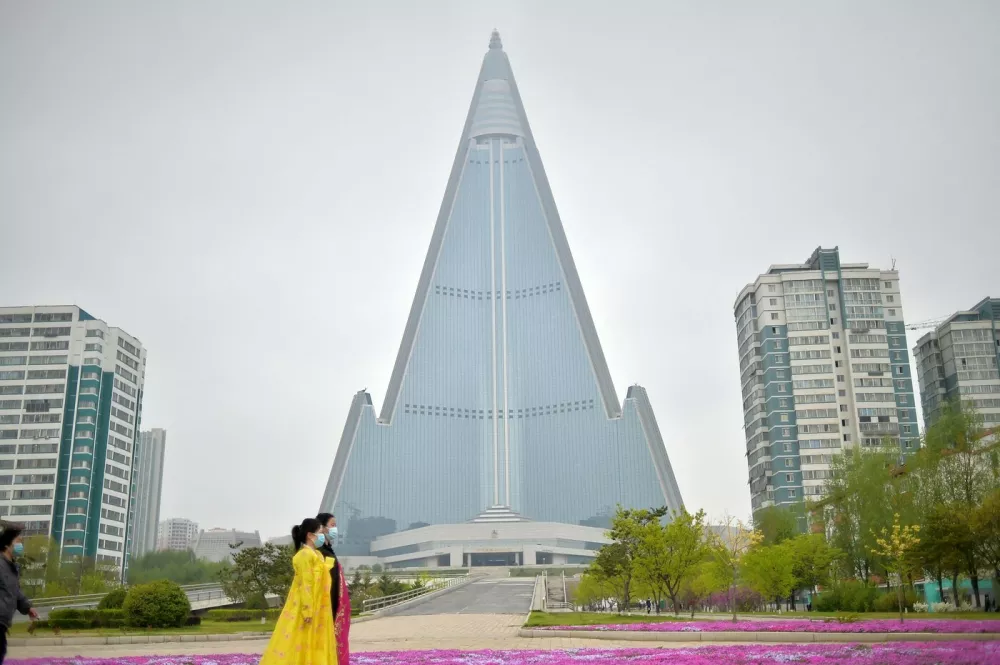 Women walk along the street before Ryugyong Hotel in Pyongyang on April 20, 2023.,Image: 770671054, License: Rights-managed, Restrictions:, Model Release: no