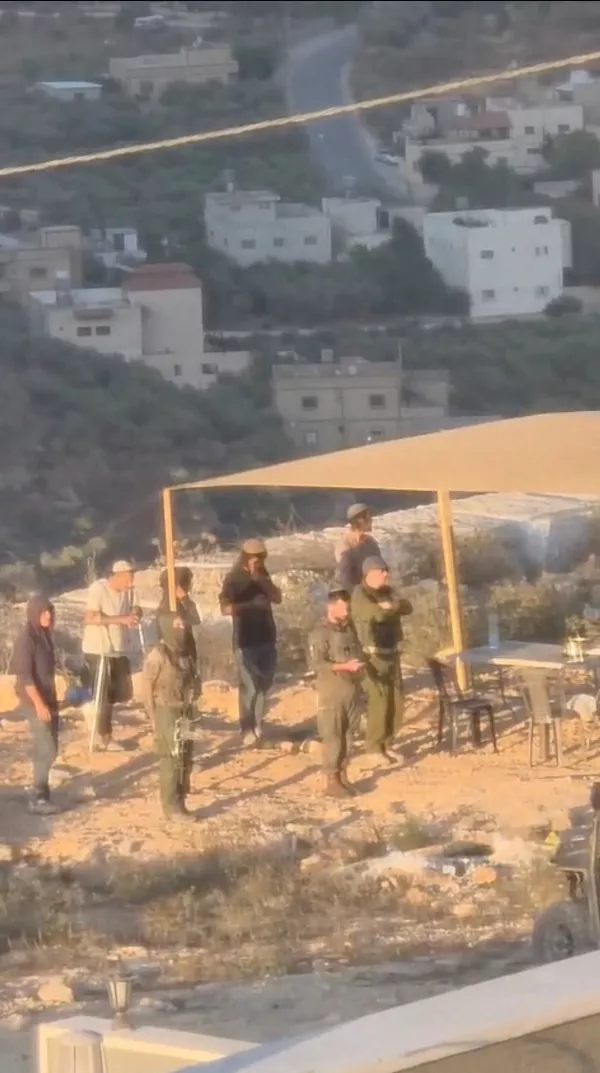 Israeli settlers and people in military uniforms stand outside a Palestinian's house in Qusra, in the Israeli-occupied West Bank, in this screengrab taken from a handout video released August 10, 2026. Video obtained by Reuters/Handout via REUTERS  THIS IMAGE HAS BEEN SUPPLIED BY A THIRD PARTY. NO RESALES. NO ARCHIVES VERIFICATION: -Buildings, road layout and wall matched satellite imagery -Hills matched topographic mapping of the area -The exact date could not be verified, but Reuters reporting based on eyewitness testimony said that Israeli settlers set up an outpost in Qusra on August 8 -The identity of the people wearing uniforms in the video could not be confirmed -No older version of the video was found posted online before August 10
