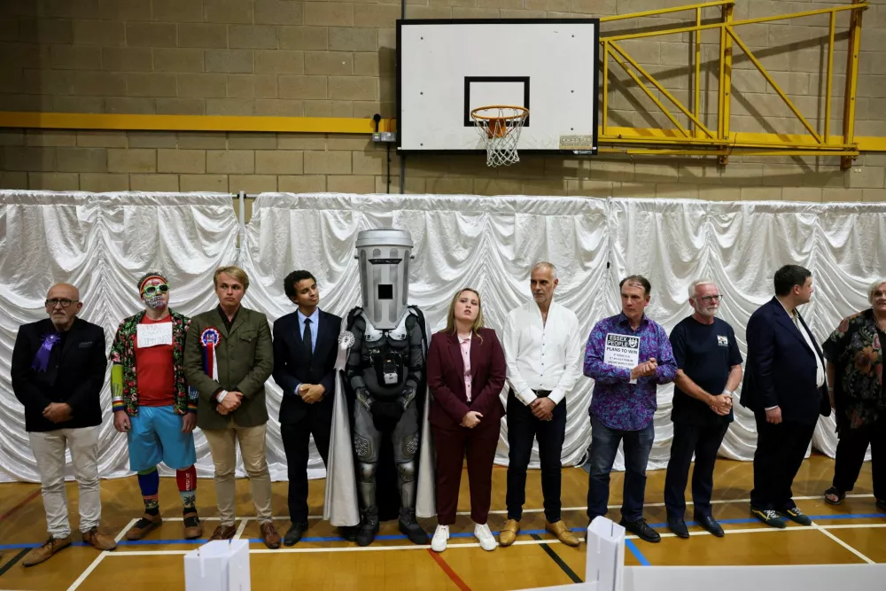 Count Binface stands with other candidates after Reform UK party leader Nigel Farage was declared the winner for the Clacton by-election, triggered by the resignation of Farage, in Essex, Britain, August 14, 2026. REUTERS/Jack Taylor REFILE - CORRECTING "GESTURES" TO "STANDS WITH".