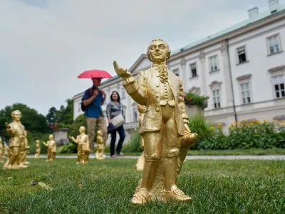 FILE - People walk by some of the 400 gold colored plastic Mozart sculptures by German artist Ottmar Hoerl from Nuremberg for the 270th birthday of composer Wolfgang Amadeus Mozart in Salzburg, Austria, Wednesday, July 15, 2026. (AP Photo/Matthias Schrader, File)