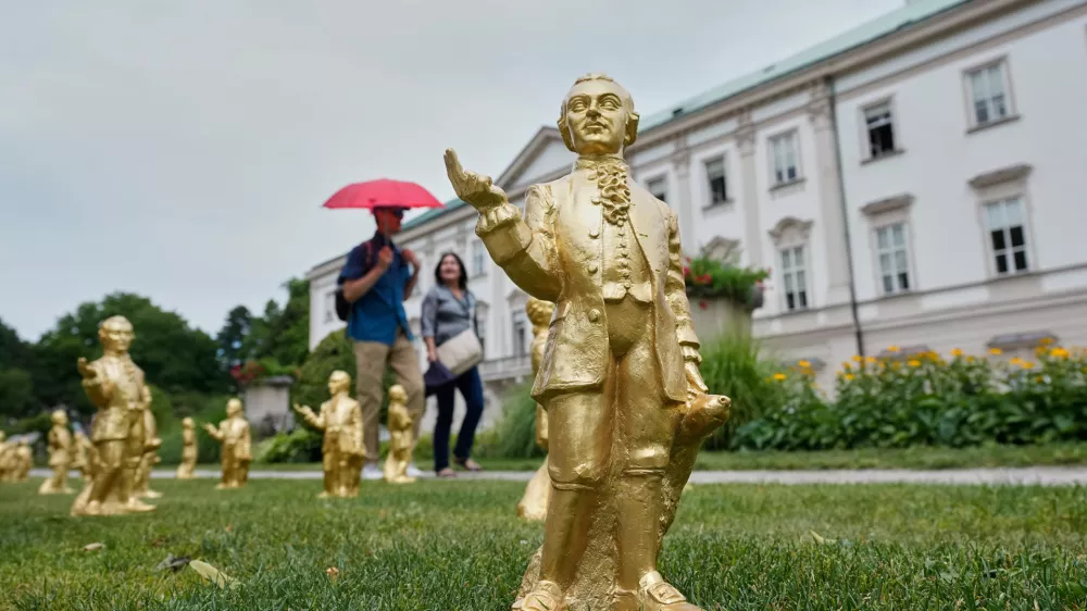 FILE - People walk by some of the 400 gold colored plastic Mozart sculptures by German artist Ottmar Hoerl from Nuremberg for the 270th birthday of composer Wolfgang Amadeus Mozart in Salzburg, Austria, Wednesday, July 15, 2026. (AP Photo/Matthias Schrader, File)