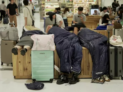 People stranded by heavy rain rest at Narita International Airport in Narita, Chiba Prefecture, Japan, August 14 2026. REUTERS/Tom Bateman   TPX IMAGES OF THE DAY