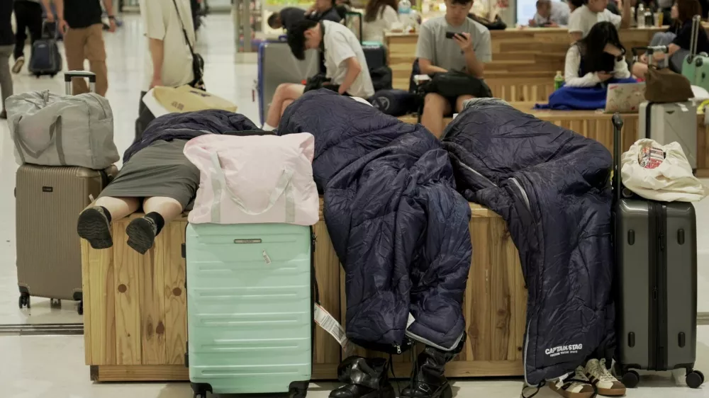 People stranded by heavy rain rest at Narita International Airport in Narita, Chiba Prefecture, Japan, August 14 2026. REUTERS/Tom Bateman   TPX IMAGES OF THE DAY