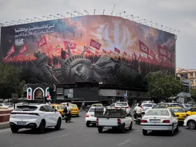 A billboard depicting a fallen Statue of Liberty and crowds carrying Iranian and Shiite flags overlooks Revolution Square as traffic drives by in Tehran, Iran, Monday, Aug. 3, 2026. (AP Photo/Vahid Salemi)