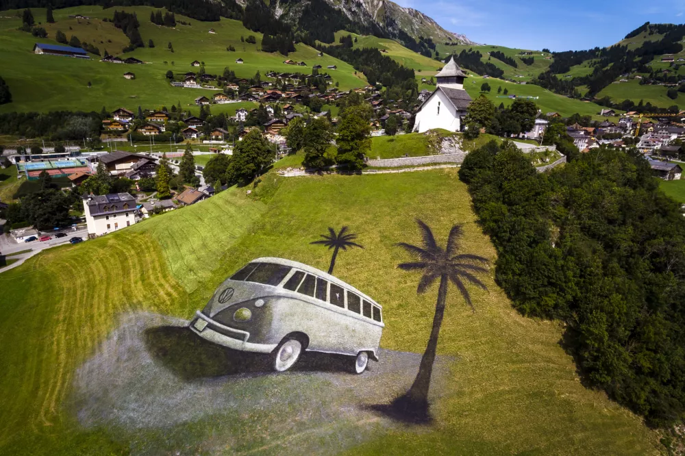 A land art painting by French artist Saype, depicting a Volkswagen (VW) bus, is pictured on a hill in Chateau d'Oex, Switzerland, Wednesday, Aug. 23, 2017. The artwork covering approximately 4200 square meters was produced with over 400 liters of biodegradable paint made from natural pigments, water and a milk protein and is part of the upcoming 20th international VW festival. (Valentin Flauraud/Keystone via AP)