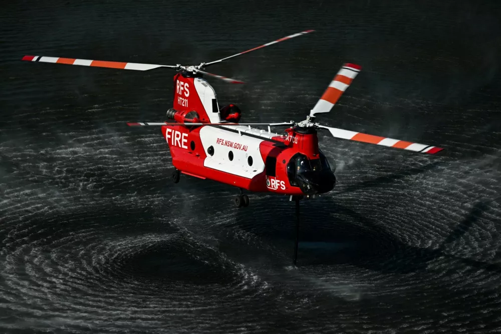 An Australian New South Wales Rural Fire Service (RFS) CH-47D Chinook water-bombing helicopter refills water over a pond during an exercise on the eve of its operational launch, near Captieux, south-western France, August 12, 2026.   PHILIPPE LOPEZ/Pool via REUTERS