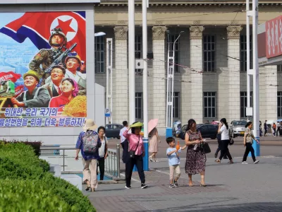 People walk in the street of the Central District in Pyongyang, North Korea, Monday, June 22, 2026. The poster reads, "Let us make strenuous efforts for the prosperity of our great state!" (AP Photo/Jon Chol Jin)