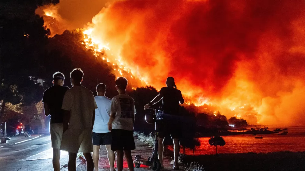 People look at a wildfire on the Adriatic coast near Omis, southern Croatia, early Friday, Aug. 14, 2026. (AP Photo/Tom Dubravec)