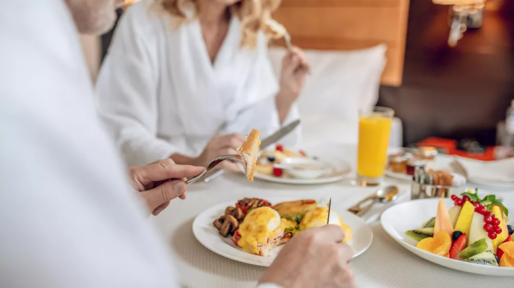 Breakfast time. A couple in white robes having breakfast and looking pleased