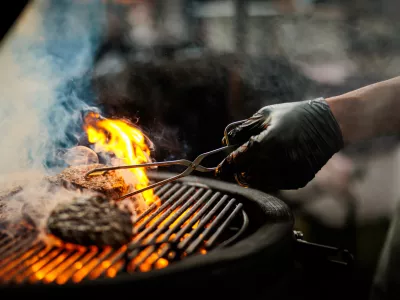 A shef turning a burger on a barbecue