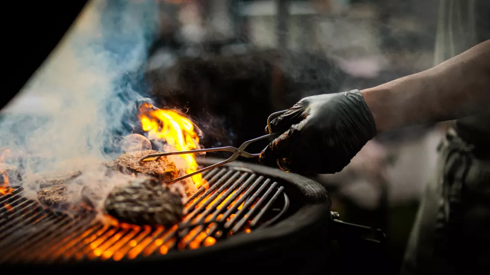 A shef turning a burger on a barbecue