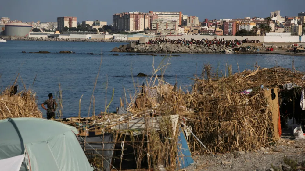 Makeshift shelters used by migrants line the coast as a crowd gathers on a breakwater in Ceuta, Spain, August 15, 2026. REUTERS/Maria Alejandra Cardona