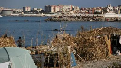 Makeshift shelters used by migrants line the coast as a crowd gathers on a breakwater in Ceuta, Spain, August 15, 2026. REUTERS/Maria Alejandra Cardona
