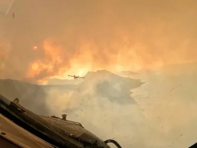 Smoke rises from a wildfire as a firefighting aircraft overflies the area, as seen from the window of another plane, in a location given as the Dalmatia region, Croatia, in this screengrab from video released on August 14, 2026. Croatian Ministry of Defence/Handout via REUTERS THIS IMAGE HAS BEEN SUPPLIED BY A THIRD PARTY