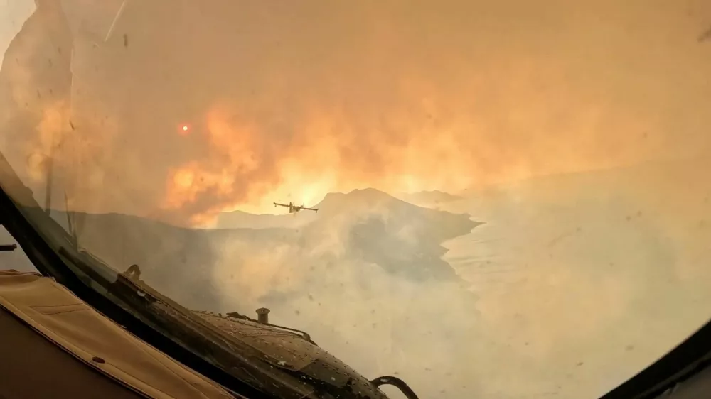 Smoke rises from a wildfire as a firefighting aircraft overflies the area, as seen from the window of another plane, in a location given as the Dalmatia region, Croatia, in this screengrab from video released on August 14, 2026. Croatian Ministry of Defence/Handout via REUTERS THIS IMAGE HAS BEEN SUPPLIED BY A THIRD PARTY