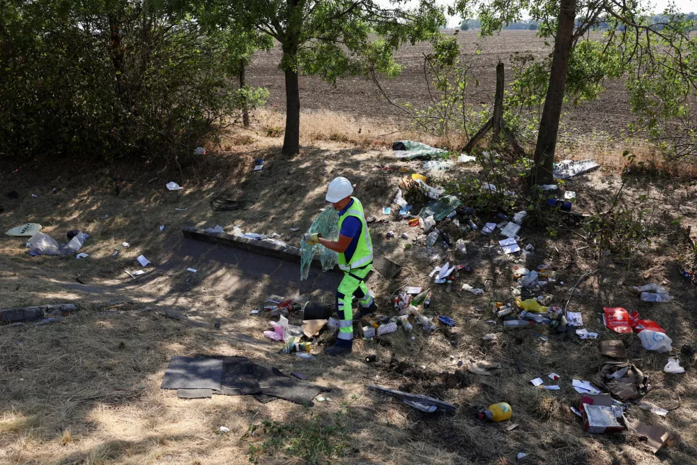 A worker of the motorway operator carries a broken glass window as they clear the wreckage at the scene of a deadly accident, where a Polish bus carrying tourists veered off the motorway and overturned, near Mezokeresztes, Hungary, April 16, 2026. REUTERS/Bernadett Szabo