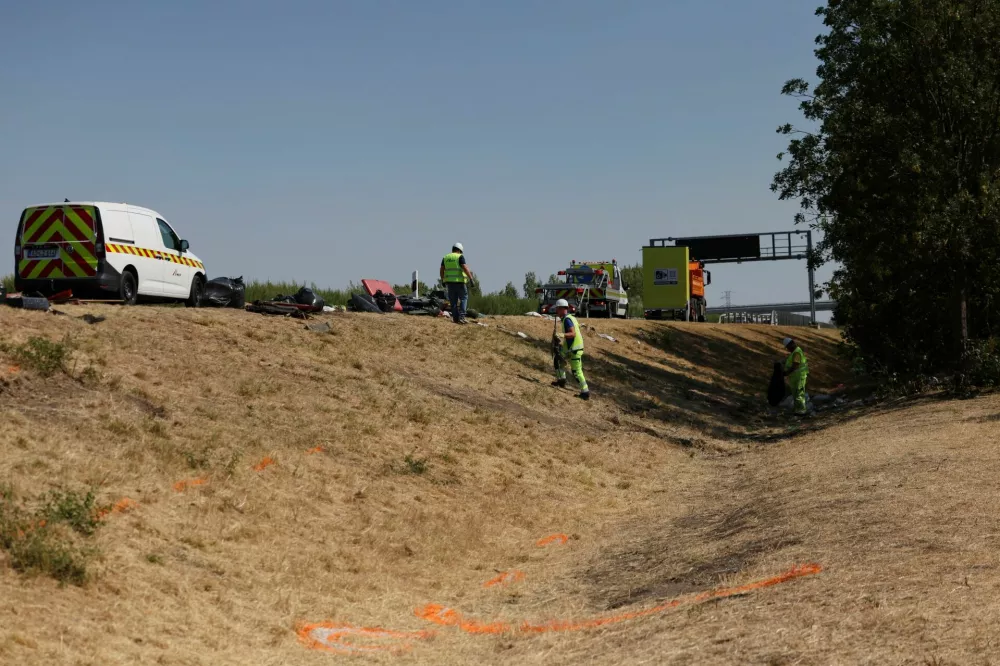 Markings made by investigators on the ground are seen in the foreground as workers of the motorway operator clear the wreckage at the scene of a deadly accident, where a Polish bus carrying tourists veered off the motorway and overturned, near Mezokeresztes, Hungary, April 16, 2026. REUTERS/Bernadett Szabo
