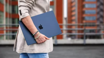Zlin, Czech Republic - April 13, 2025: Businesswoman with Apple laptop MacBook Air walking outside of office building