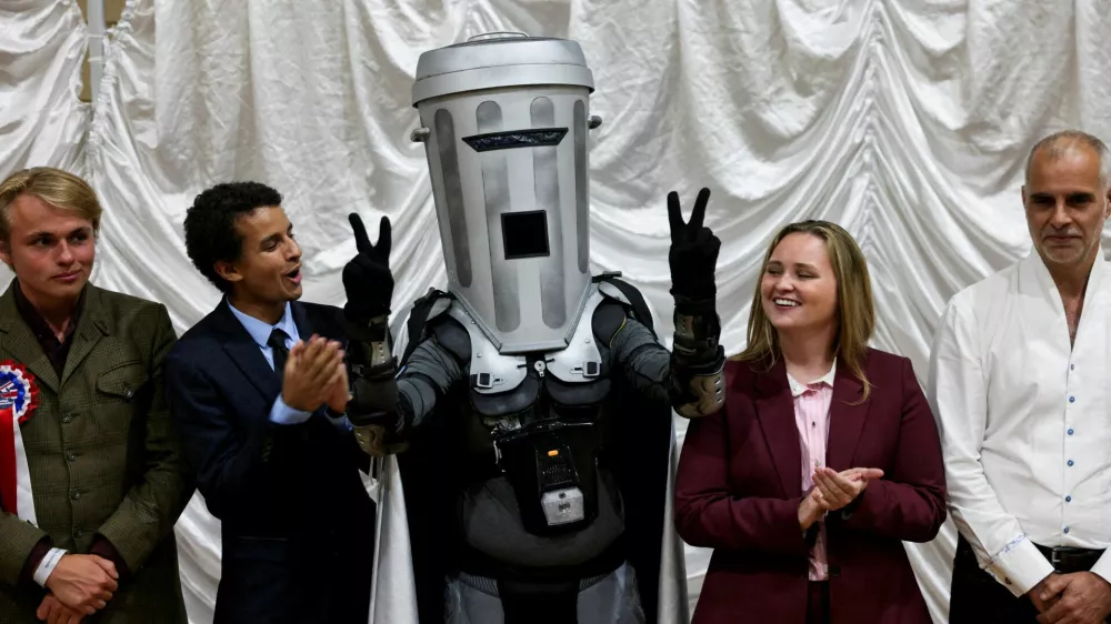 Count Binface gestures while standing with other candidates after Reform UK party leader Nigel Farage was declared the winner for the Clacton by-election, triggered by the resignation of Farage, in Essex, Britain, August 14, 2026. REUTERS/Jack Taylor   TPX IMAGES OF THE DAY    REFILE - UPDATING GRAMMAR