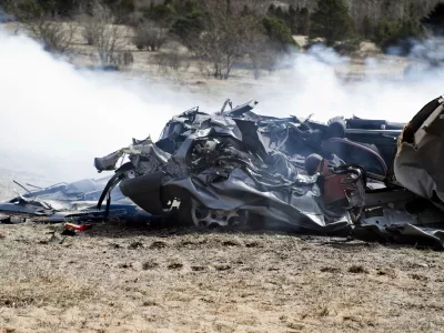Car run over by a tank on a battlefield. Totally wrecked and smoke still around it. Trees and bushes in the back ground